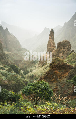 Mountain peaks of Xo-Xo valley of Santa Antao island, Cape Verde. Many cultivated plants growing in the valley between high rocks. Arid and erosion mountain peaks sun light. Sahara dust in the air Stock Photo