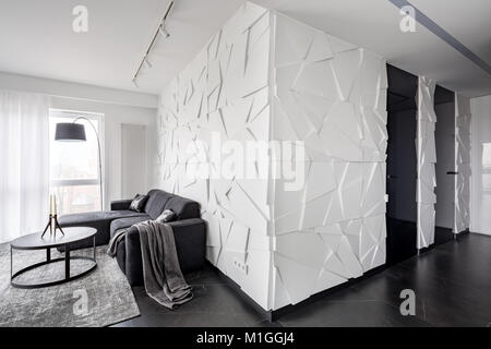 Black and white apartment with couch, round table and modern, textured wall Stock Photo