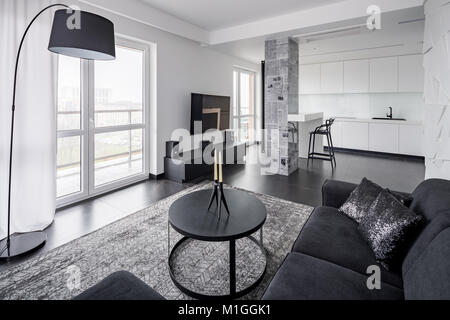 Home interior with black couch, round table and lamp
