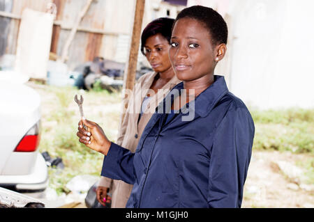 Young woman mechanic holds a key next to the owner of this car. Stock Photo