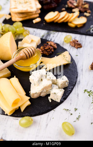Cheese plate. Assortment of cheese with walnuts, bread an honey on stone slate plate Stock Photo