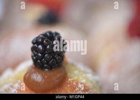macro food image of homemade fresh donut or doughnuts with apple and cinnamon jam and a close up of the blackberry fruit on top with bight background Stock Photo