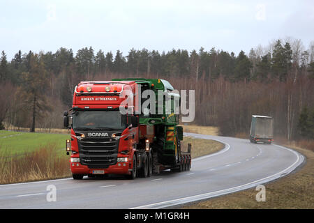 SALO, FINLAND - JANUARY 26, 2018: Scania R580 semi hauls John Deere W440 combine on gooseneck trailer as wide load on a rural highway in South of Finl Stock Photo