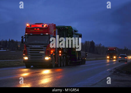 SALO, FINLAND - JANUARY 26, 2018: Scania R560 semi hauls John Deere combine on gooseneck trailer as wide load transport at night in South of Finland. Stock Photo