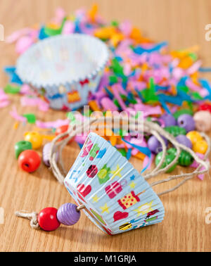 Budgerigar, Budgie (Melopsittacus undulatus). Assembly instruction for budgeriar toy, made from paper muffin liners and wooden beads . German Stock Photo