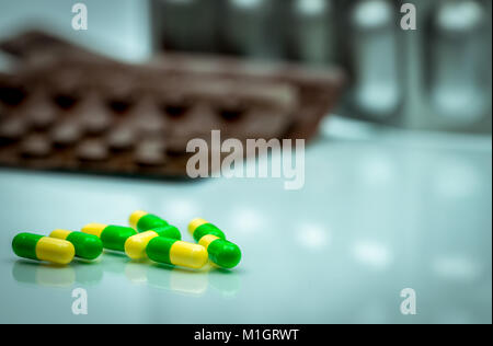 Green, yellow tramadol capsule pills on blurred blister pack background with copy space. Cancer pain management. Opioid analgesics. Drug abuse in teen Stock Photo
