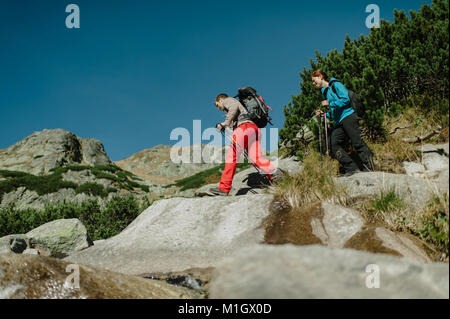 Low angle view of a young couple nordic walking in mountains. Stock Photo