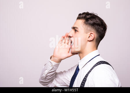 Closeup side view profile portrait, angry upset young man, worker, employee, business man, hand to mouth, open mouth yelling, isolated white backgroun Stock Photo