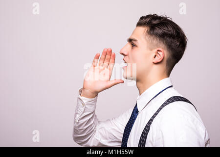 Closeup side view profile portrait, angry upset young man, worker, employee, business man, hand to mouth, open mouth yelling, isolated white backgroun Stock Photo