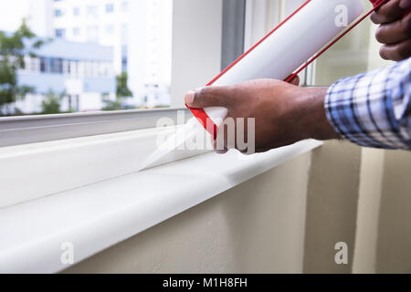 Close-up Of Person Hand Applying Silicone Sealant With Silicone Gun On Window Stock Photo