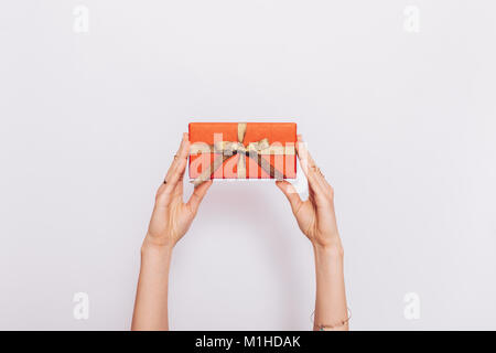 Red gift box with ribbon in female hands over head on white background Stock Photo