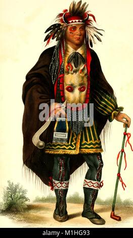 Full length, color illustration of Chippeway Chief Okeemakeequid, wearing red and black face paint, an elaborate beaded and feathered Sioux outfit, with headdress, boots, and cape, over a striped jacket, a beaded hip bag, and neck slung animal head bag, and holding a club in one hand and a long pipe in the other, from the book 'Indian Biography' authored by Thatcher BB (Benjamin Bussy), 1825. Courtesy Internet Archive. () Stock Photo