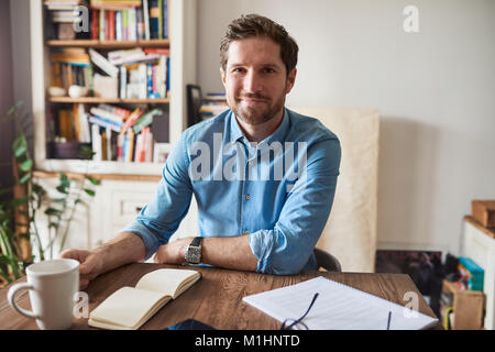 Smiling man working at his living room table at home Stock Photo