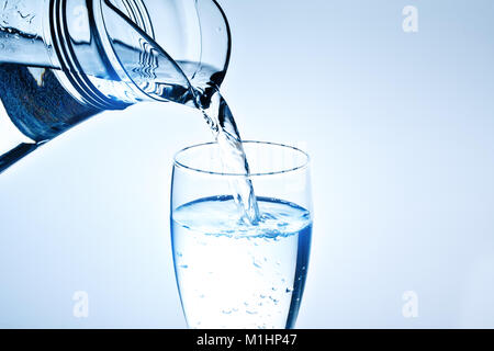 Fresh drinking water is poured in a glass. Blue background. Stock Photo