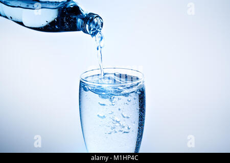 Fresh drinking water is poured in a glass. Blue background. Stock Photo