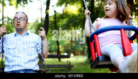 Portrait of man and girl with down syndrome swinging Stock Photo