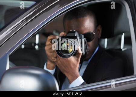Young African Photographer With Camera Sitting Inside Car Stock Photo