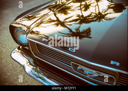 MIAMI - JANUARY 14, 2018: Palm tree silhouettes reflect on the hood of an antique Ford Mustang car parked on Ocean Drive. Stock Photo