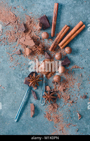 Flat lay with spoons, chocolate pieces, spices, anise stars, cinnamon and cocoa on a stone background. Ingredients for a dessert. Homemade sweets phot Stock Photo