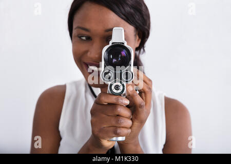Close-up Of A Smiling African Woman Looking Through Lens Of Retro Camera Stock Photo