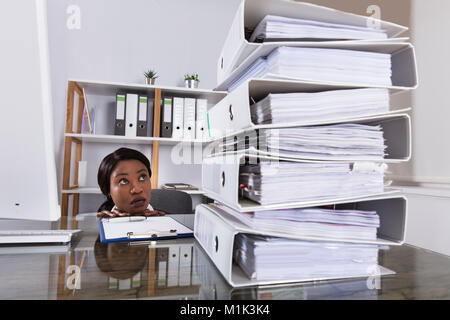Young African Woman Looking At Stack Of Folders On Desk In Office Stock Photo
