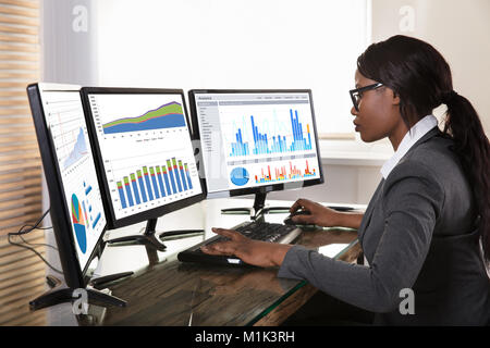 Young African Businesswoman Looking At Graphs On Computer In Office Stock Photo