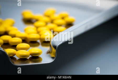 Macro shot detail of yellow round sugar coated tablets pills on stainless steel drug tray Stock Photo