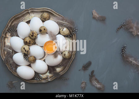 White organic chicken and quail eggs in vintage plate on gray background. Top view and copy space. Stock Photo