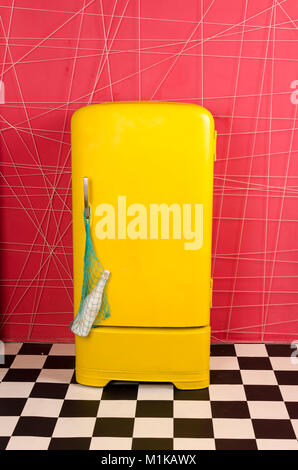 yellow old vintage retro refrigerator on a pink background with string bag and champagne bottle Stock Photo