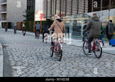 Tourists on a Berlin City Bike Tour cycling on the road paved with setts along the river Spree near Reichstag building Stock Photo