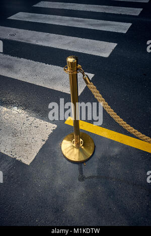 A gold rope barrier and stand at a pedestrian road crossing - special vip everyday Stock Photo