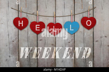 Hello weekend written on hanging red and blue wooden  hearts, on background of used weathered scaffolding wood Stock Photo