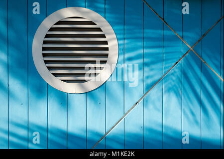 Textured background of tropical palm frond shadows waving in bright sun across bright blue nautical-theme wall Stock Photo