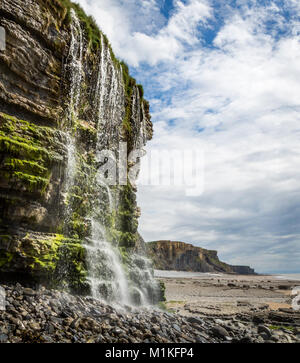 Nant Cwm Mawr waterfall cascading over Jurassic lias limestone cliffs to the beach on the Glamorgan Heritage Coast South Wales UK Stock Photo