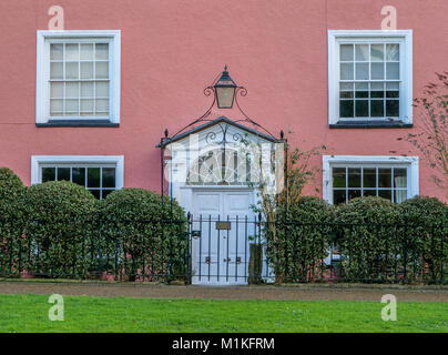 Pink painted Georgian house with wrought iron arched gate with lamp on Cathedral Green in Wells Somerset UK Stock Photo