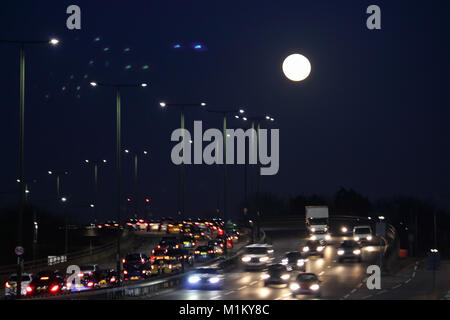 Hanworth London UK. 31st January 2018. The super blue moon seen low in the sky above traffic queuing on the A316 at Apex Corner in Hanworth, South West London. Credit: Julia Gavin/Alamy Live News Stock Photo