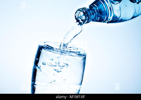 Fresh drinking water is poured in a glass. Blue background. Stock Photo