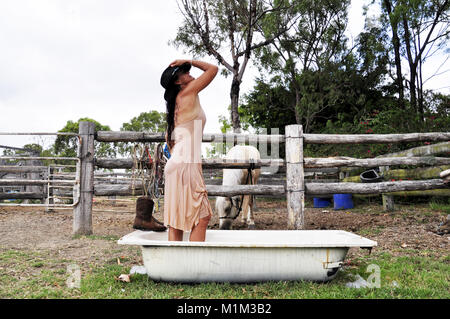 COWGIRL STANDING IN BATH WITH WET DRESS ON Stock Photo - Alamy