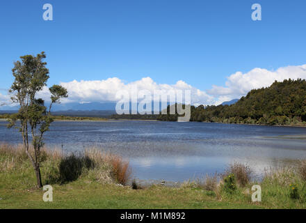 View out over Okarito lagoon looking inland towards mountains in the Southern Alps from Okarito on the west coast of South Island, New Zealand. Stock Photo