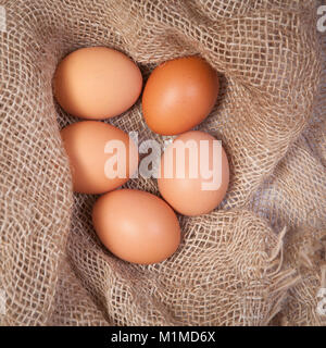 Yellow eggs lie on a canvas on a white wooden table. Stock Photo