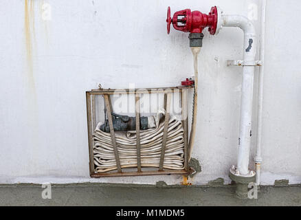 A coiled Fire Hose on a wall Stock Photo