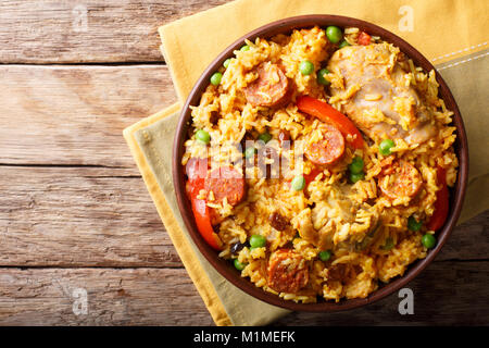 Arroz Valenciana with rice, meat, sausage, raisins, vegetables and spices close up in a bowl on the table. horizontal top view from above Stock Photo
