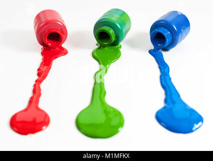 Red, green and blue paint pots with paint spill Stock Photo