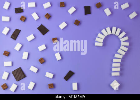 Sugar background. Sugar cubes shaped as a question mark sign, brown and white sugar cubes and chocolate pieces on purple background. Stock Photo
