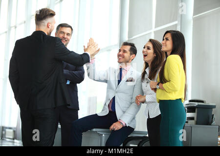 Happy successful multiracial business team giving a high fives gesture as they laugh and cheer their success Stock Photo
