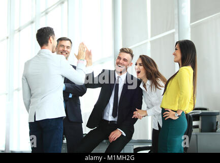 Happy successful multiracial business team giving a high fives gesture as they laugh and cheer their success Stock Photo