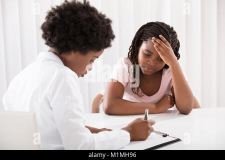Portrait Of Female Doctor Comforting Depressed Patient Stock Photo