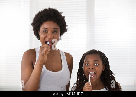 African Mother And Daughter Brushing Their Teeth In The Bathroom Stock Photo