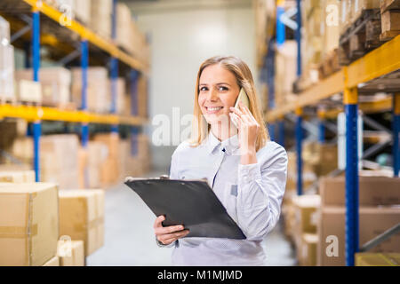 Woman warehouse worker or supervisor with smartphone. Stock Photo