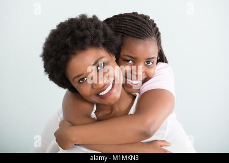 Portrait Of A Daughter Embracing Her Mother From Behind Against White Background Stock Photo